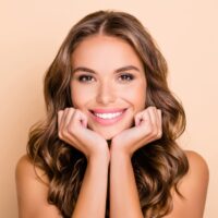 Woman smiling and holding her hands under her chin